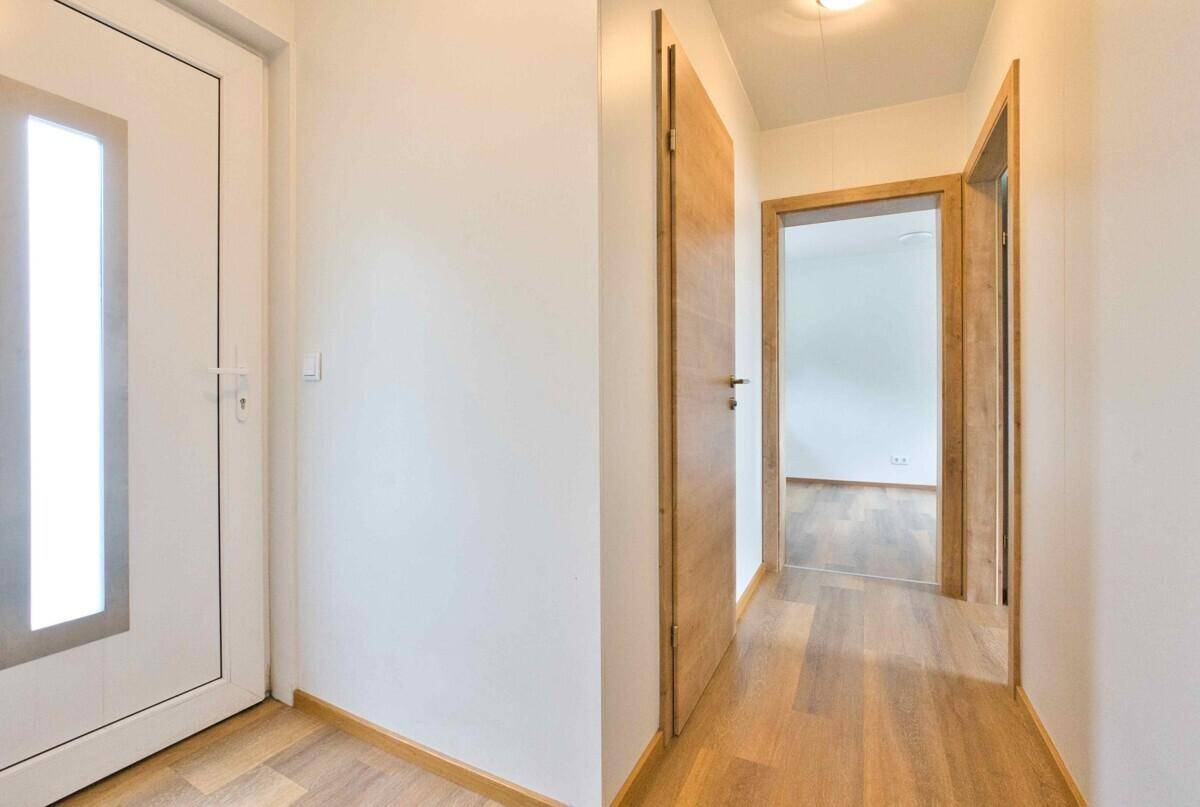 Heller Flur mit Holzboden und modernen Holztüren, die zu den Zimmern führen.