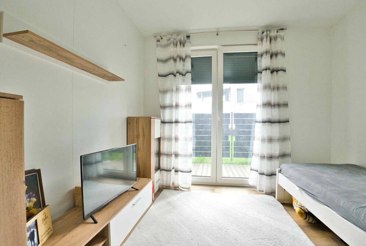 Schlafzimmer mit Einzelbett, Fernseher und Zugang zu einem Außenbereich.