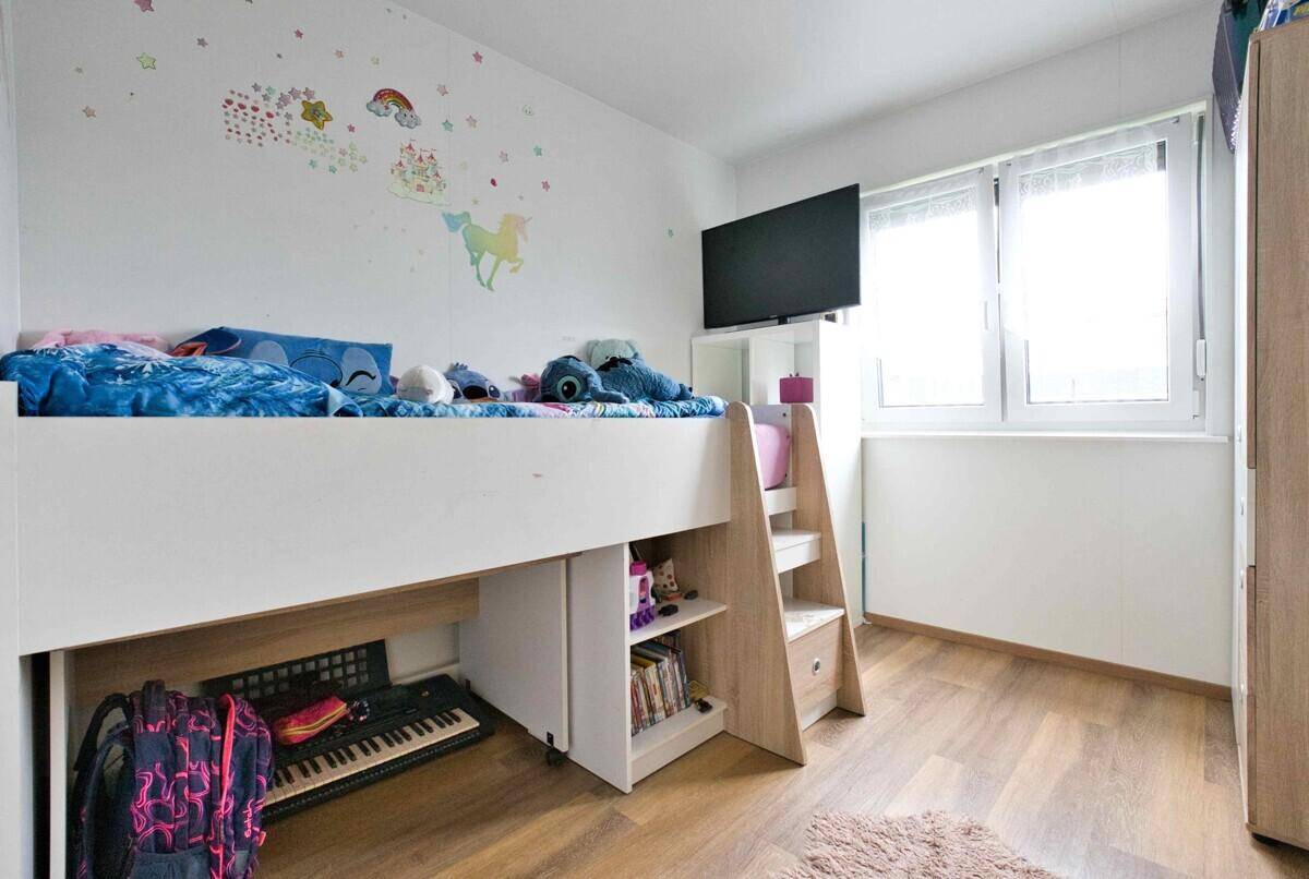 Kinderzimmer mit Hochbett, Schreibtisch und fröhlichen Wanddekorationen.