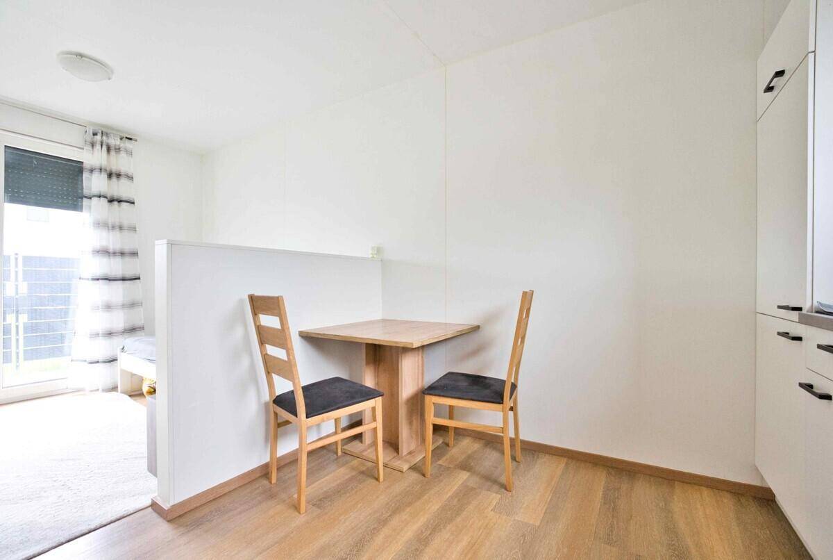 Kleiner Essbereich mit Holztisch und zwei Stühlen, ideal für Mahlzeiten.