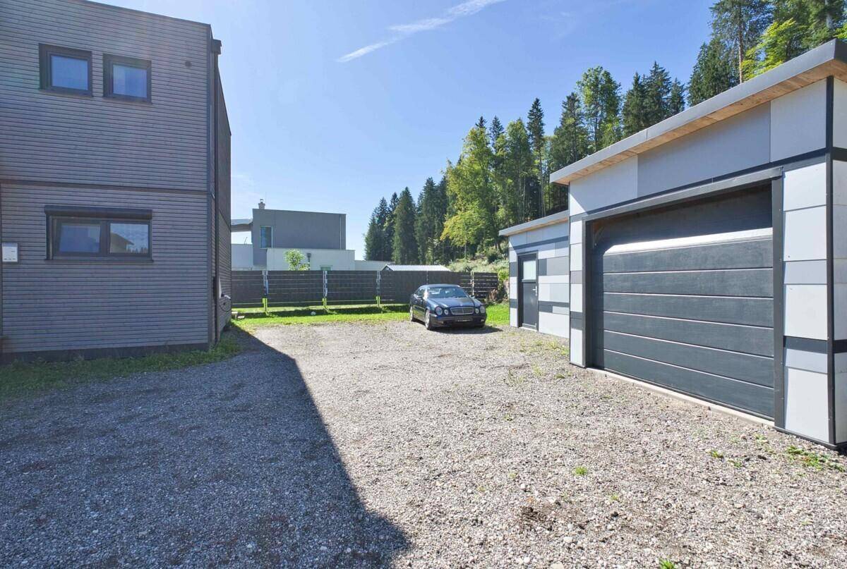 Außenansicht des Anwesens mit Kiesauffahrt, separater Garage und umgebender Naturkulisse.