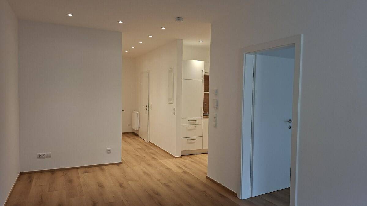 Heller Flur mit Holzboden und Blick in eine moderne Küchenzeile mit Einbauschränken.