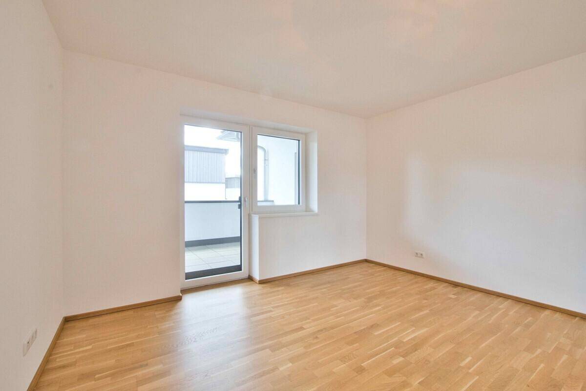 Geräumiges Zimmer mit Parkettboden und direktem Zugang zum Balkon.