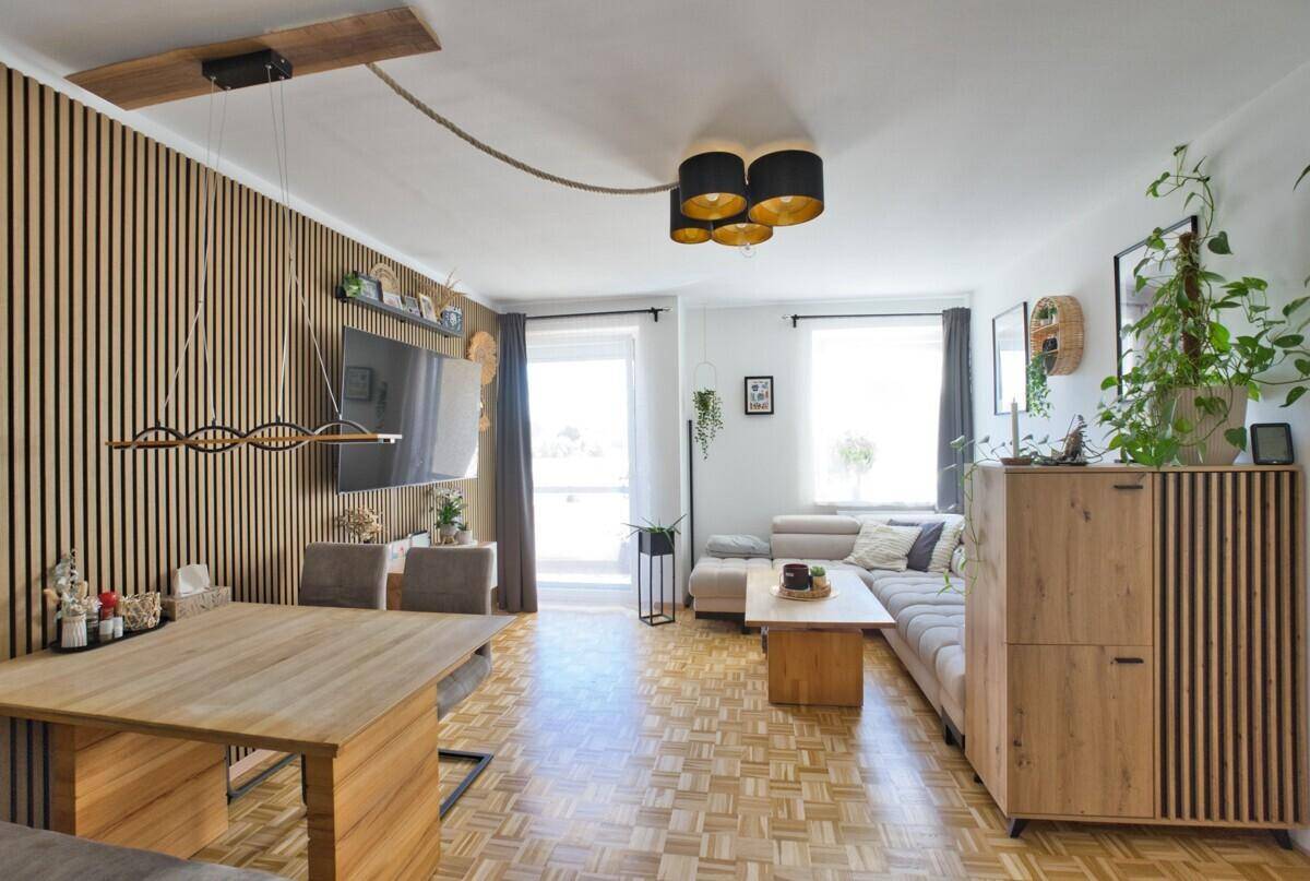Geräumiger Wohn- und Essbereich mit Parkettboden, großen Fenstern und modernem Design.