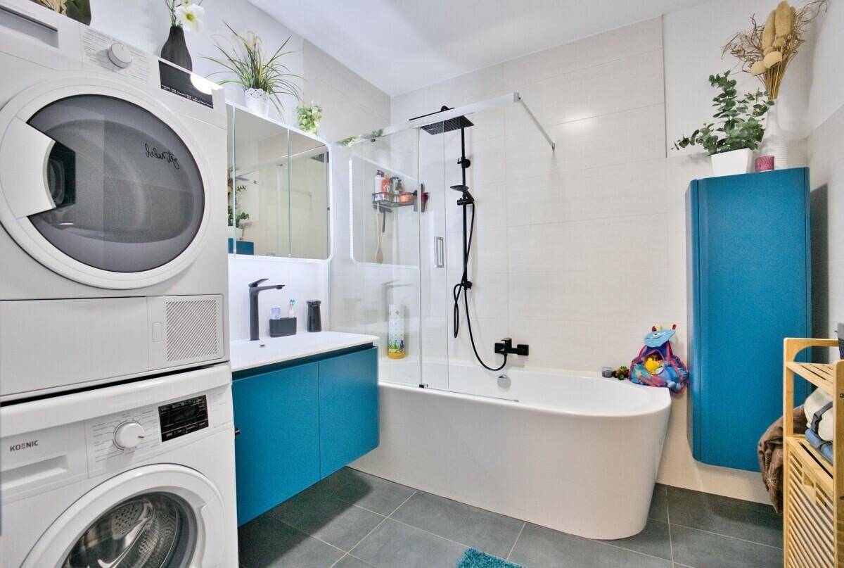Modernes Badezimmer mit Badewanne, Dusche, Waschmaschine und Trockner.