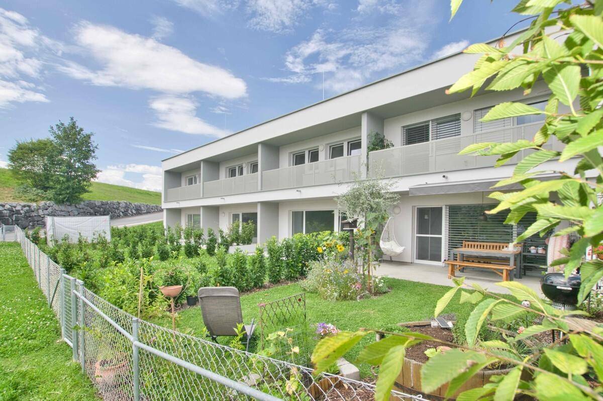 Gepflegter Gartenbereich mit verschiedenen Pflanzen, Sitzgelegenheiten und Zugang zur Terrasse.