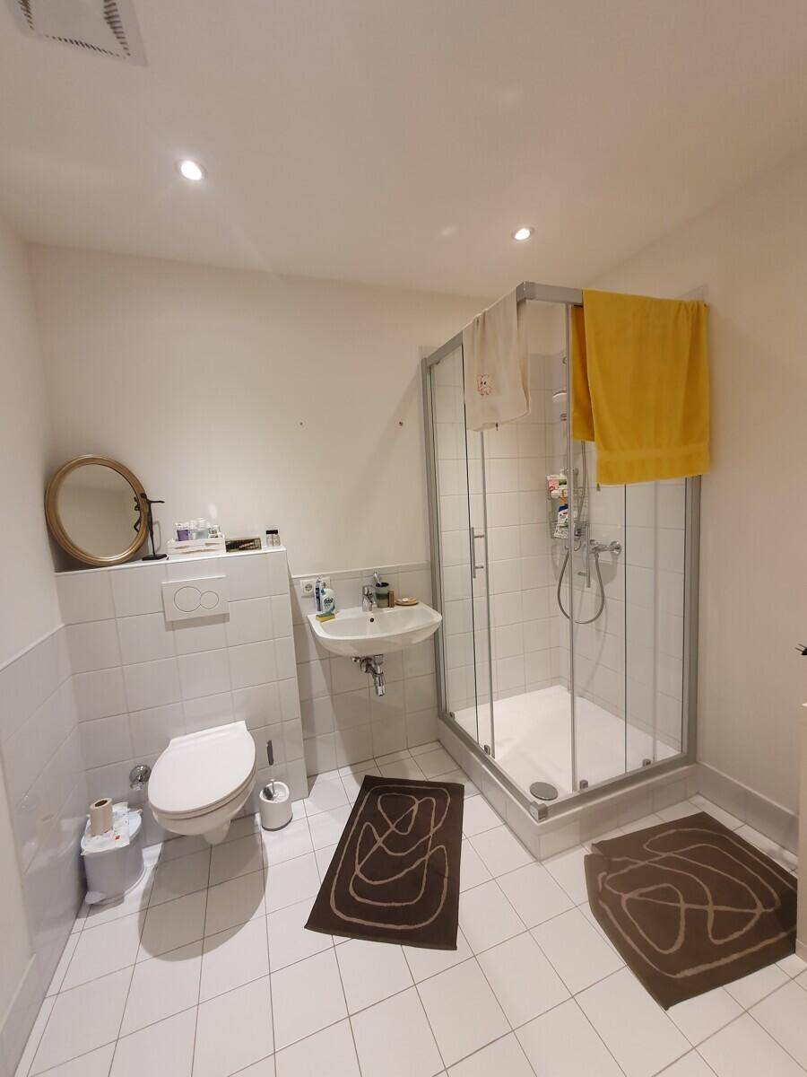 Modernes Badezimmer mit Duschkabine, WC und Waschbecken, ausgestattet mit weißen Fliesen.