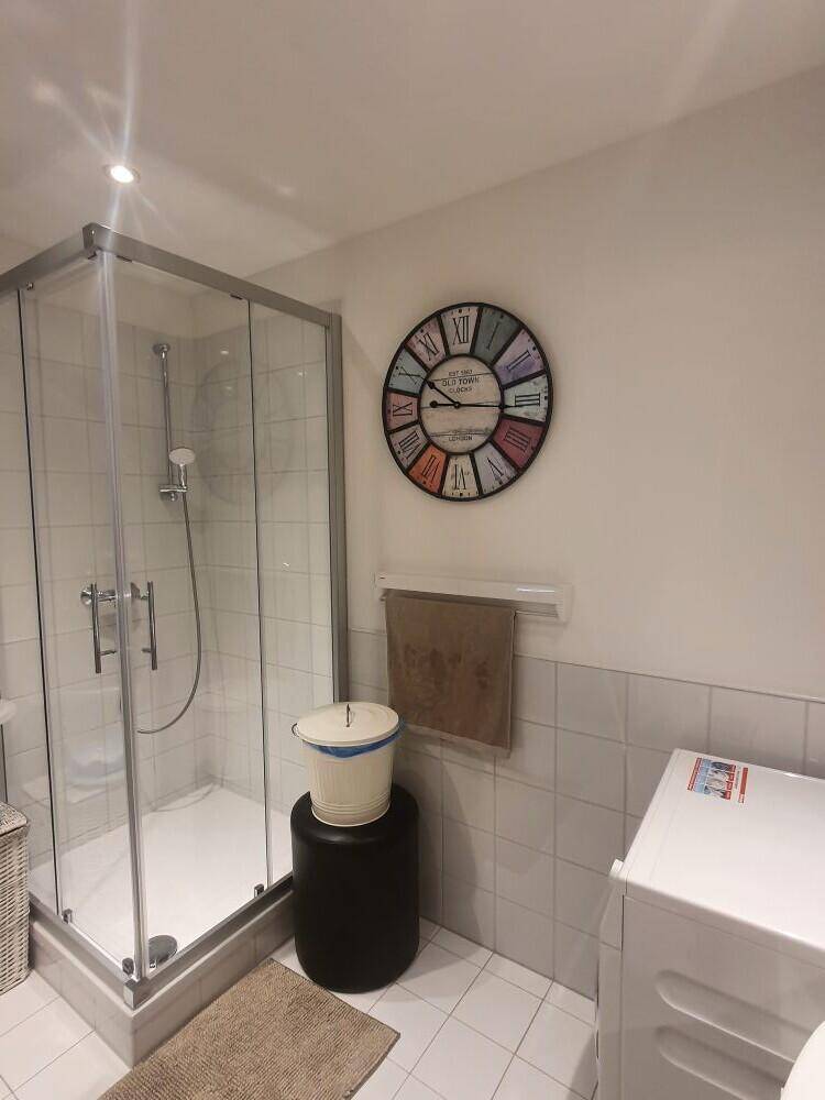 Modernes Badezimmer mit Duschkabine, Waschmaschine und Handtuchheizkörper, funktional und hell gefliest.