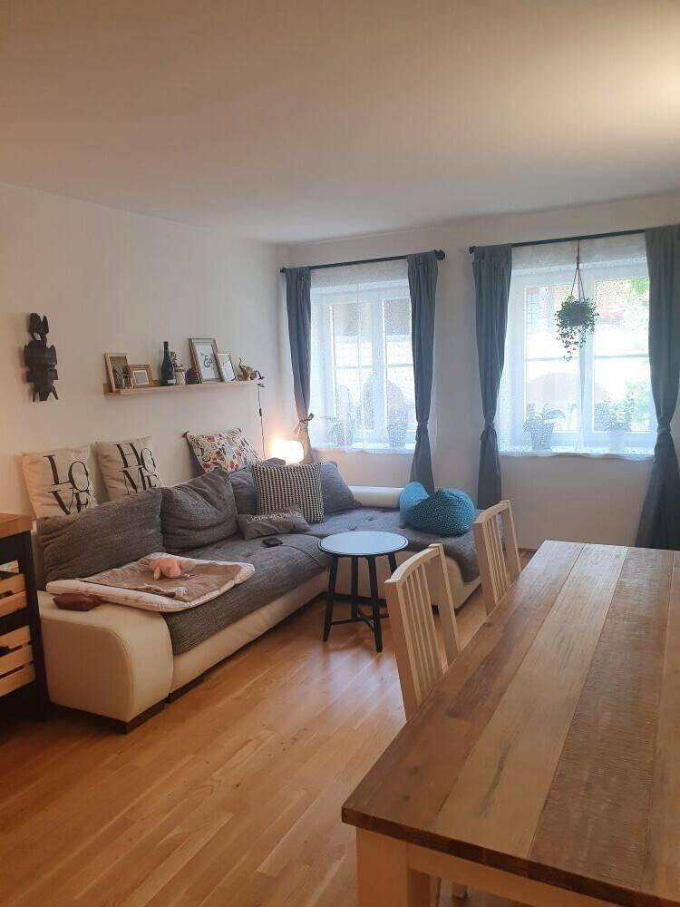 Heller Wohn-Essbereich mit bequemer Sofalandschaft, Esstisch und Holzboden, ideal für geselliges Beisammensein.