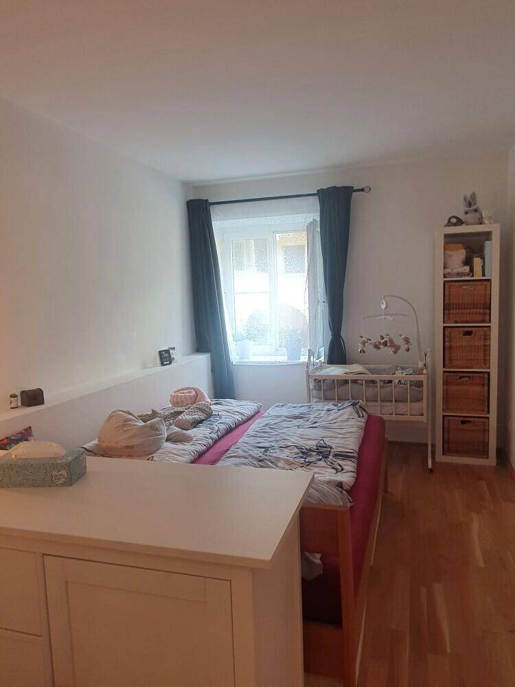 Gemütliches Schlafzimmer mit Doppelbett, Babybett und Regal, bietet eine ruhige Rückzugsmöglichkeit.
