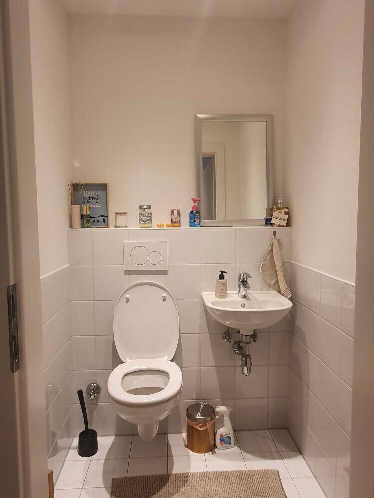 Kleines Gäste-WC mit Wand-WC und Handwaschbecken, praktisch und hell gefliest für Besucher.