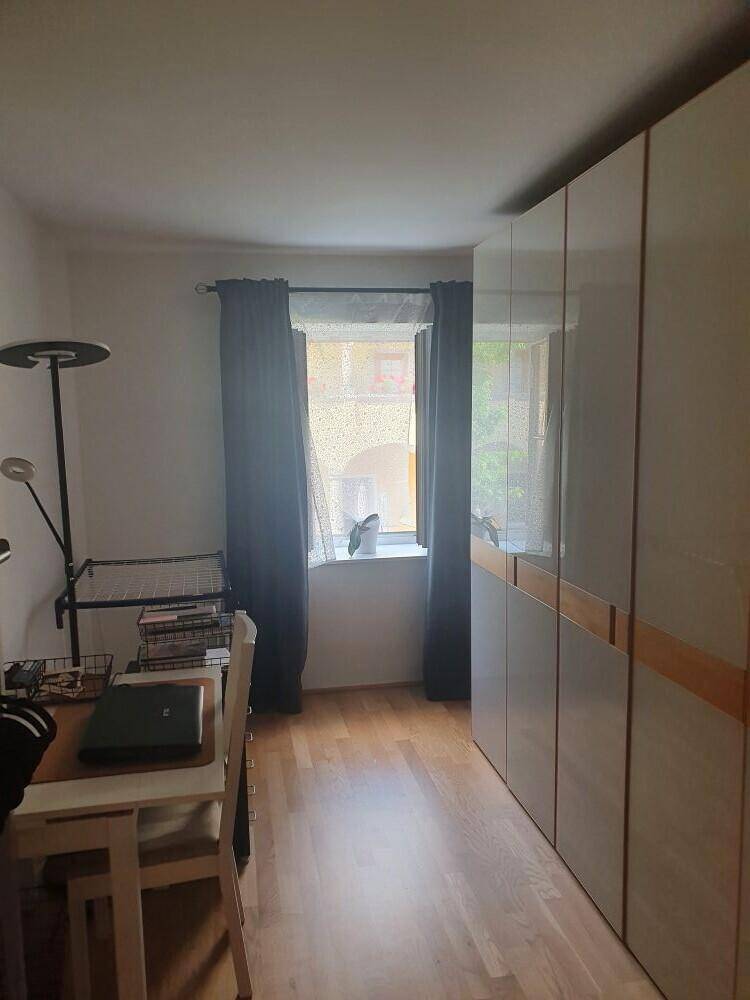 Helles Arbeitszimmer mit Schreibtisch, Stuhl und großem Kleiderschrank, ideal für Home-Office oder Studium.