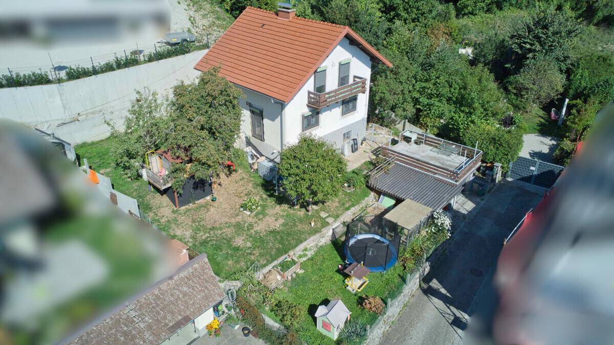 Übersicht des Einfamilienhauses von oben mit Garten, Terrasse und umliegender Natur.