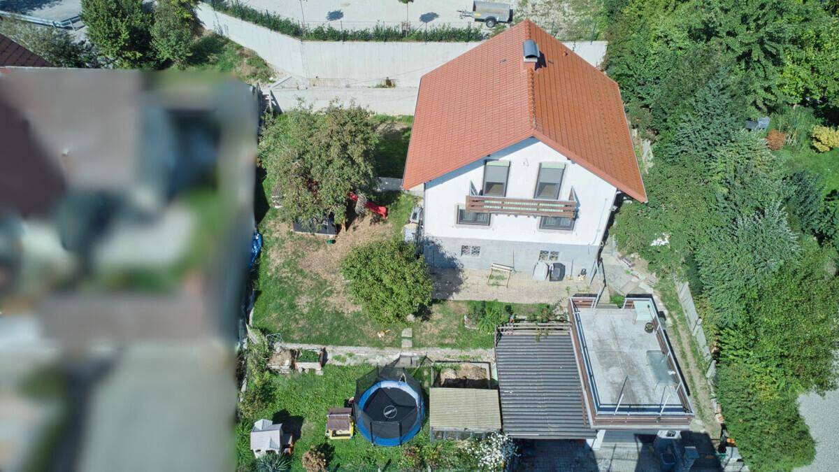 Luftaufnahme des Einfamilienhauses mit Garten, Terrasse und umliegender Vegetation.