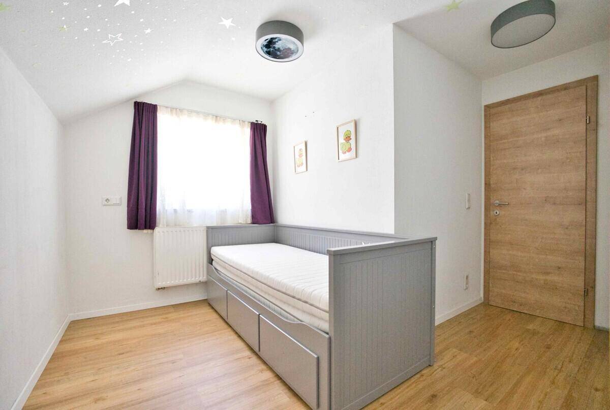 Kinderzimmer mit Tagesbett, Laminatboden und Sternenmuster an der Decke.