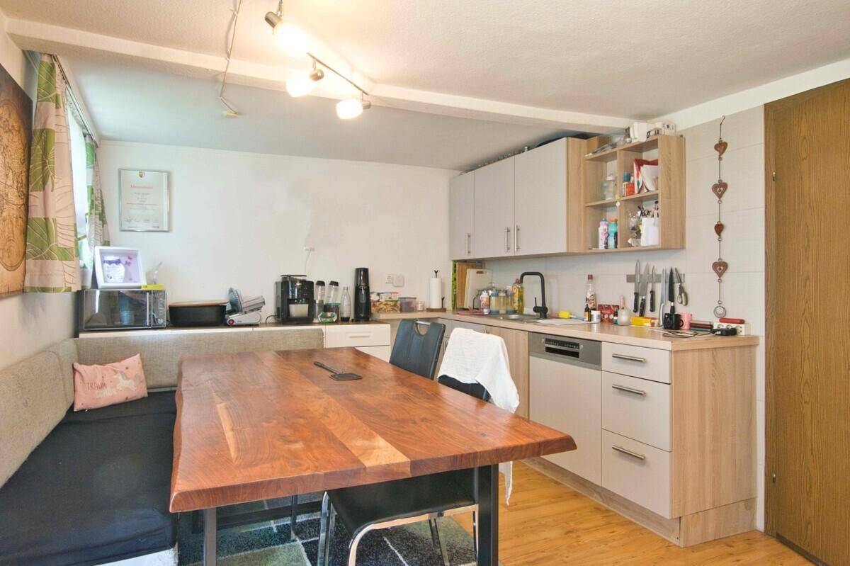 Gemütliche Wohnküche mit Holztisch, integrierter Sitzbank und modernen Küchenschränken.