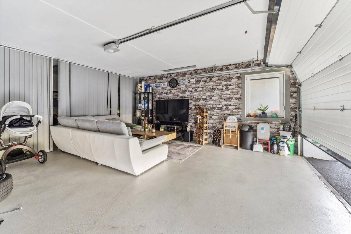Geräumige Garage, umfunktioniert als Wohnraum mit Sofa und Fernseher.