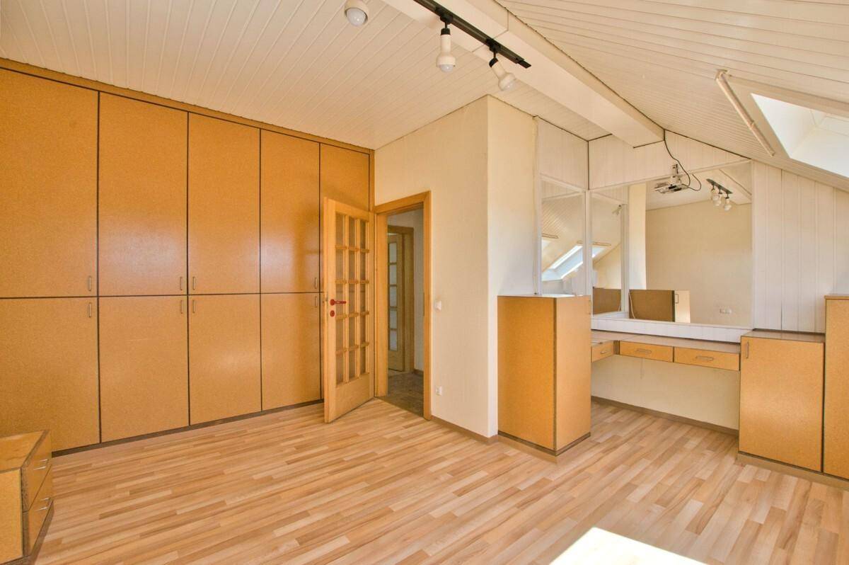 Helles Dachzimmer mit Holzfußboden, Einbauschränken und einem integrierten Schminktisch.