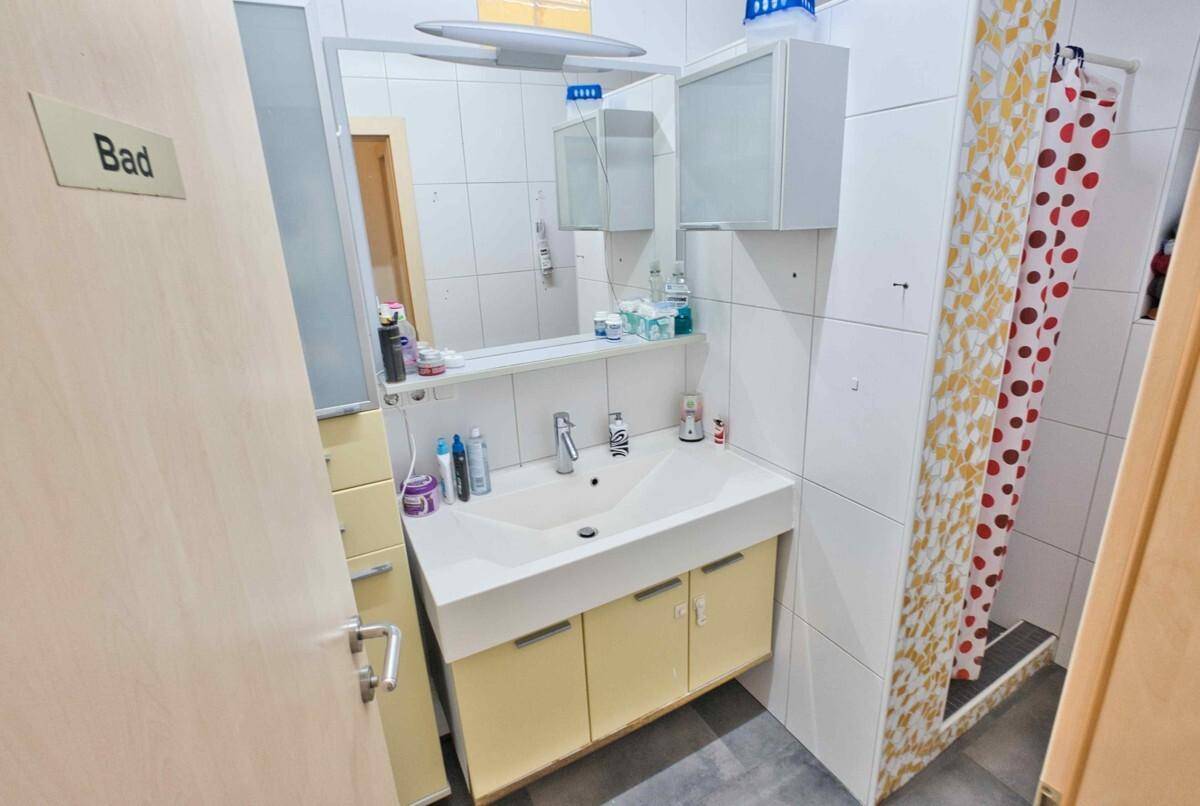 Badezimmer mit Waschbecken, Spiegelschrank und Duschbereich mit Duschvorhang.