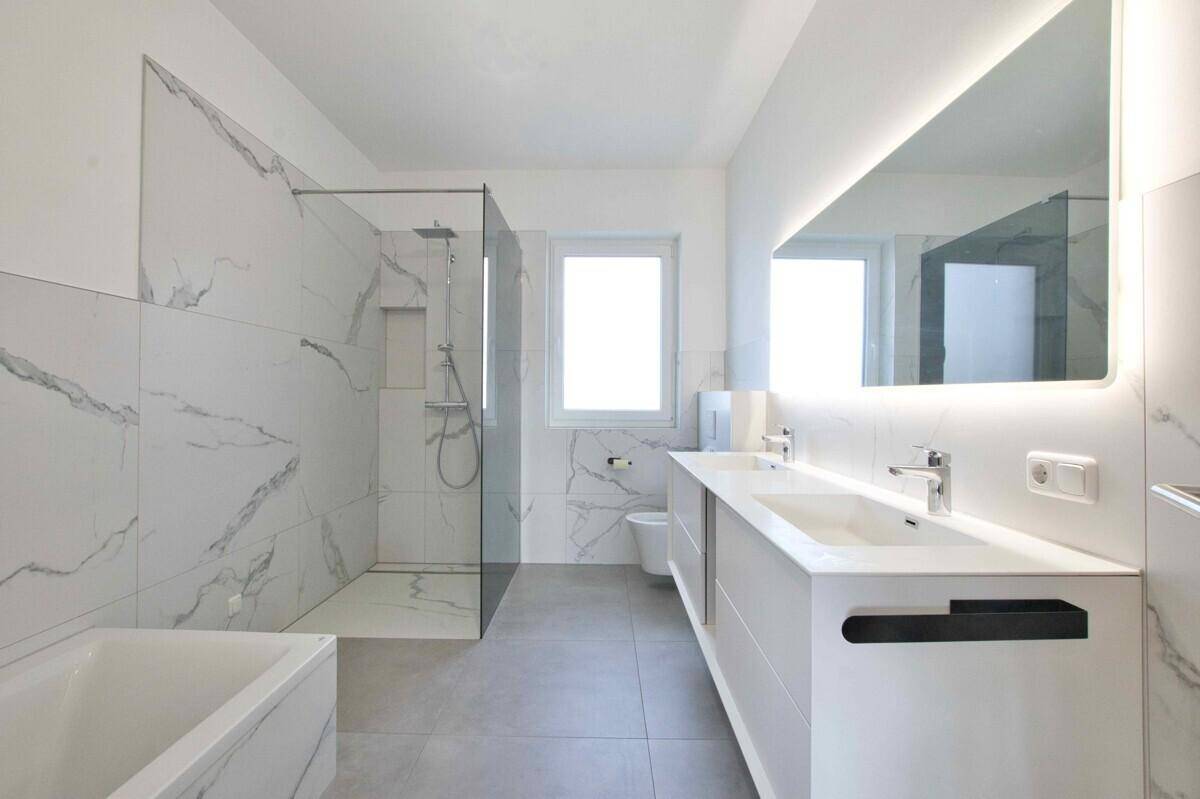 Modernes Badezimmer mit Doppelwaschbecken, großer Dusche und Badewanne.
