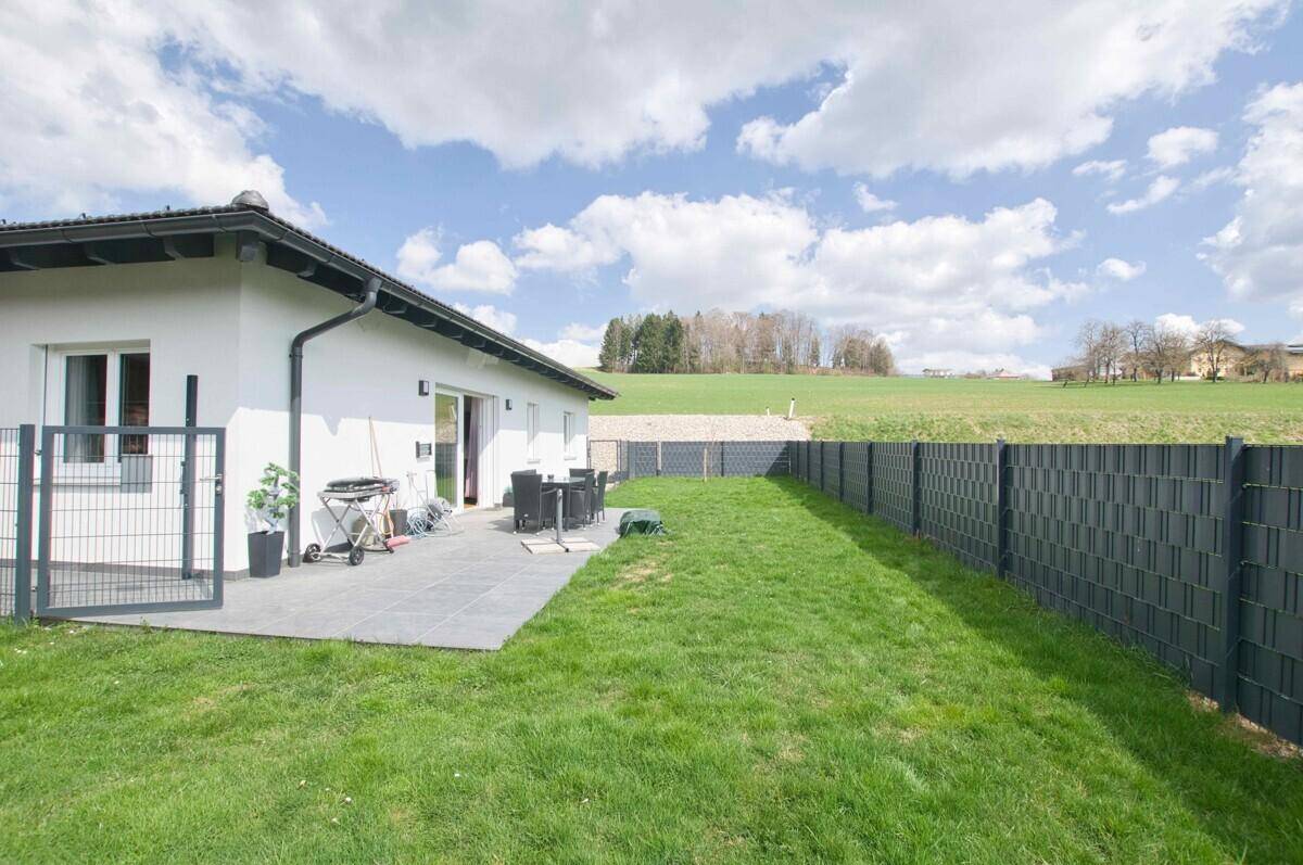 Gepflegter Garten mit Rasenfläche und einer Terrasse mit Sitzgelegenheiten.