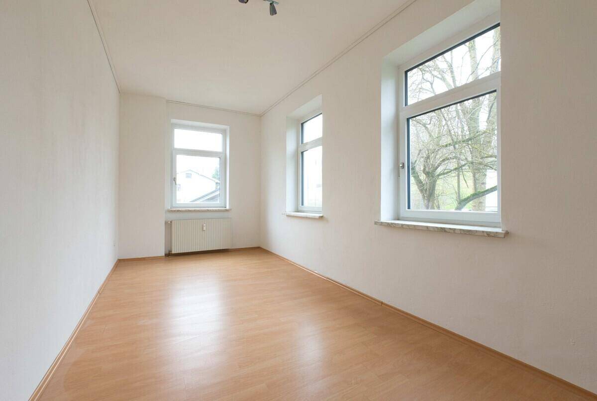 Lichtdurchflutetes Zimmer mit Laminatboden und Blick ins Grüne, ideal als Schlafzimmer.