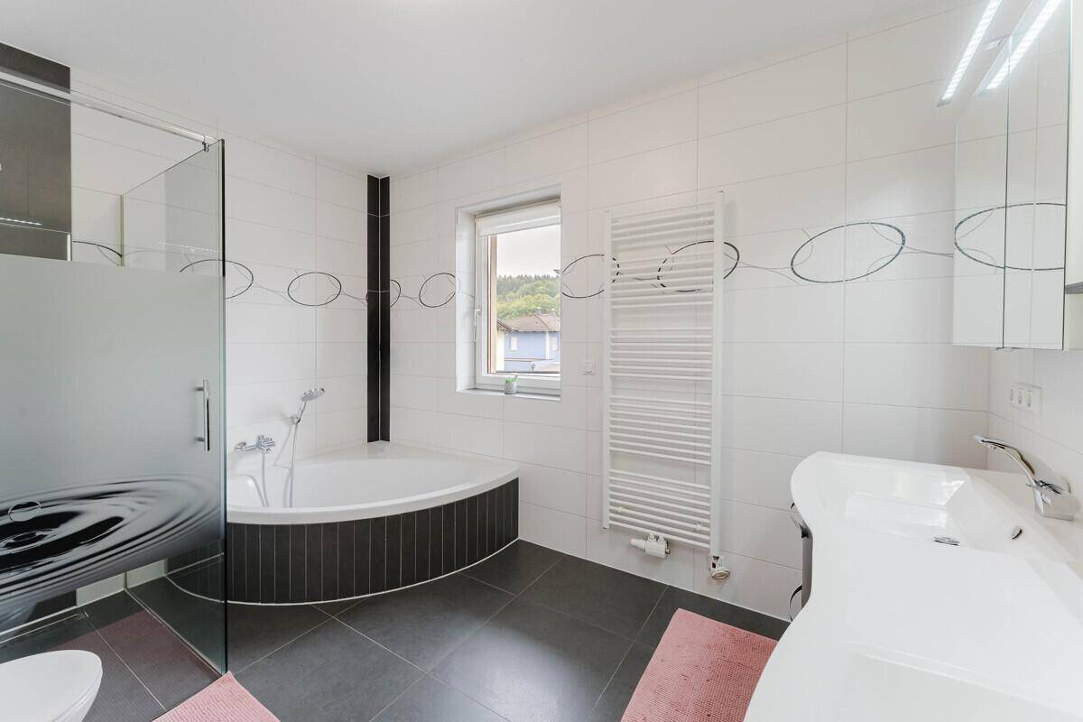 Modernes Badezimmer mit Eckbadewanne, Dusche, Doppelwaschbecken und Handtuchheizkörper.