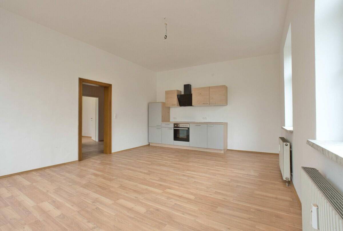 Geräumige Küche mit Laminatboden und neuer Einbauküche, die auf weitere Einrichtung wartet.