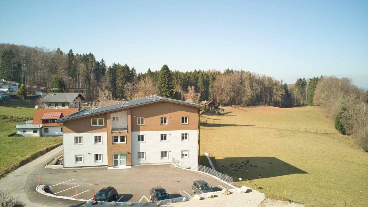 Gebäude in ländlicher Umgebung mit Parkplätzen und umgeben von Wiesen und Wäldern.