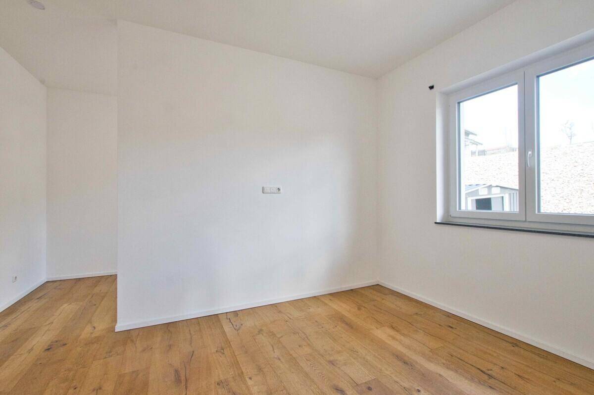 Leeres Zimmer mit schönem Holzboden und viel Tageslicht, ideal als Schlaf- oder Arbeitszimmer.