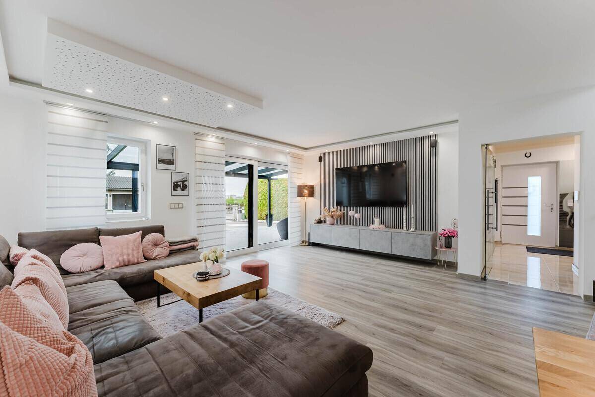 Geräumiges Wohnzimmer mit bequemer Sitzecke, stilvoller Einrichtung und hellem Laminatboden.