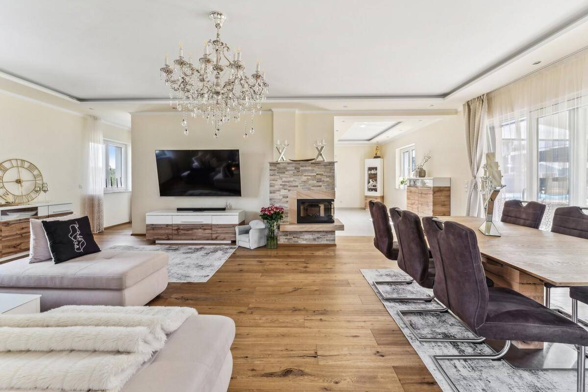 Eleganter Wohn-Essbereich mit Holzboden, Kamin und großem Esstisch für gesellige Runden.