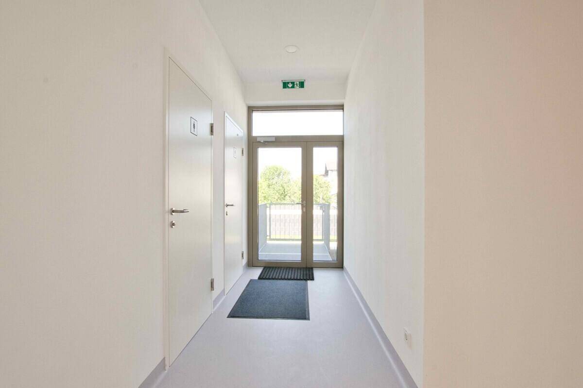 Heller Flur mit Ausgangstür und weiteren Türen, gut beleuchtet und geräumig.