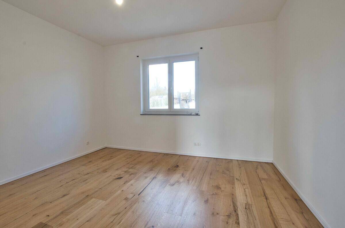 Helles Schlafzimmer mit Holzboden und Fenster, bereit zur individuellen Gestaltung.