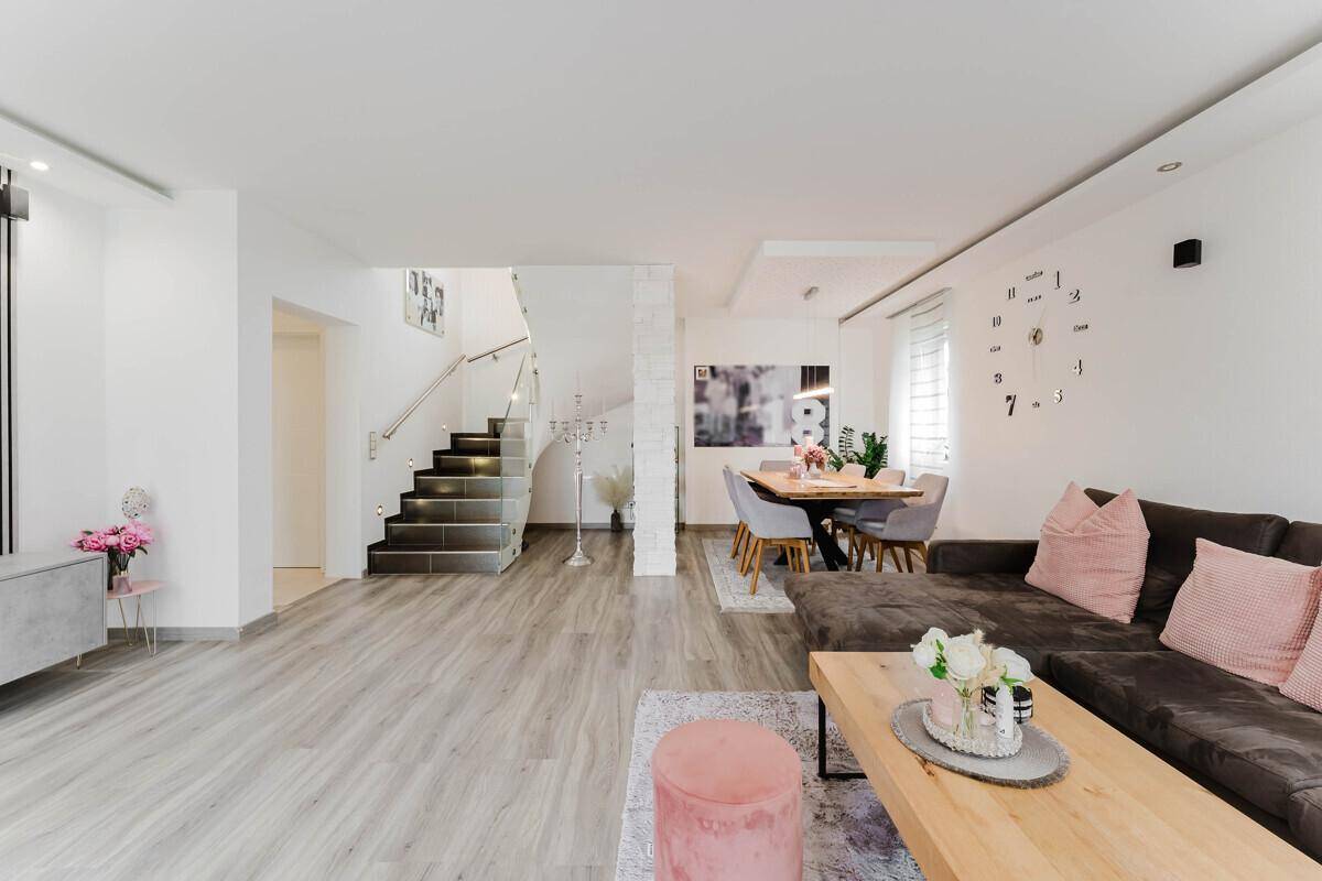 Weitläufiger Wohn-Essbereich mit Laminatboden, bequemer Sitzecke und offener Treppe.