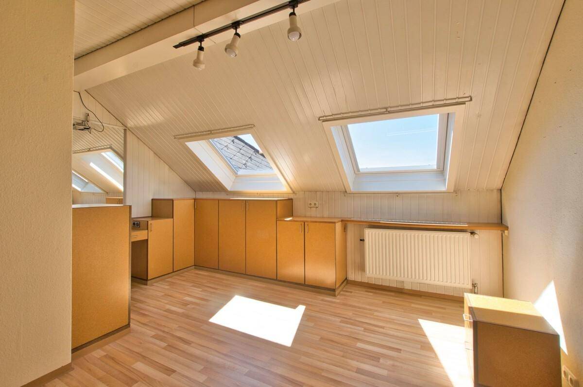 Dachgeschosszimmer mit Holzfußboden, Einbauschränken und zwei Dachfenstern für viel Licht.