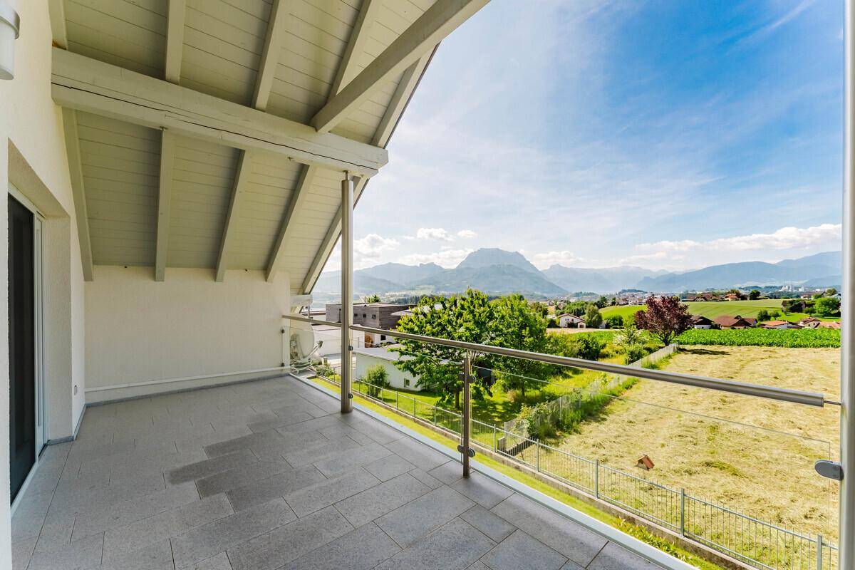 Großer Balkon mit Fliesenboden, Glasgeländer und beeindruckendem Panoramablick auf die Berge.
