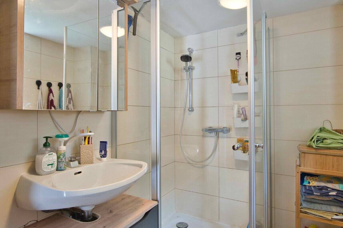 Modernes Badezimmer mit Waschbecken, Spiegelschrank und Duschkabine.