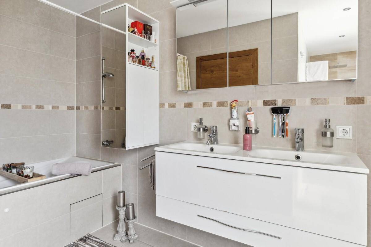 Geräumiges Badezimmer mit Doppelwaschbecken, Badewanne und hellen Fliesen.