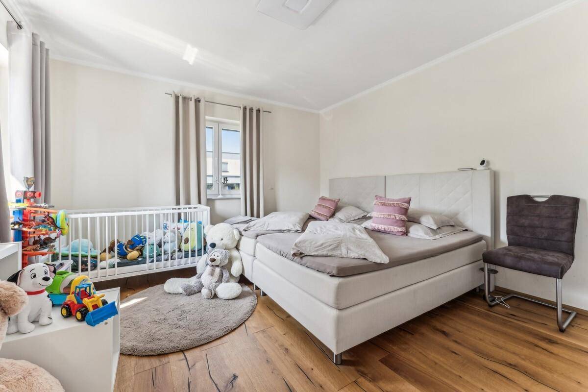 Helles Kinderzimmer mit Holzboden, weißem Bett und Spielzeug.