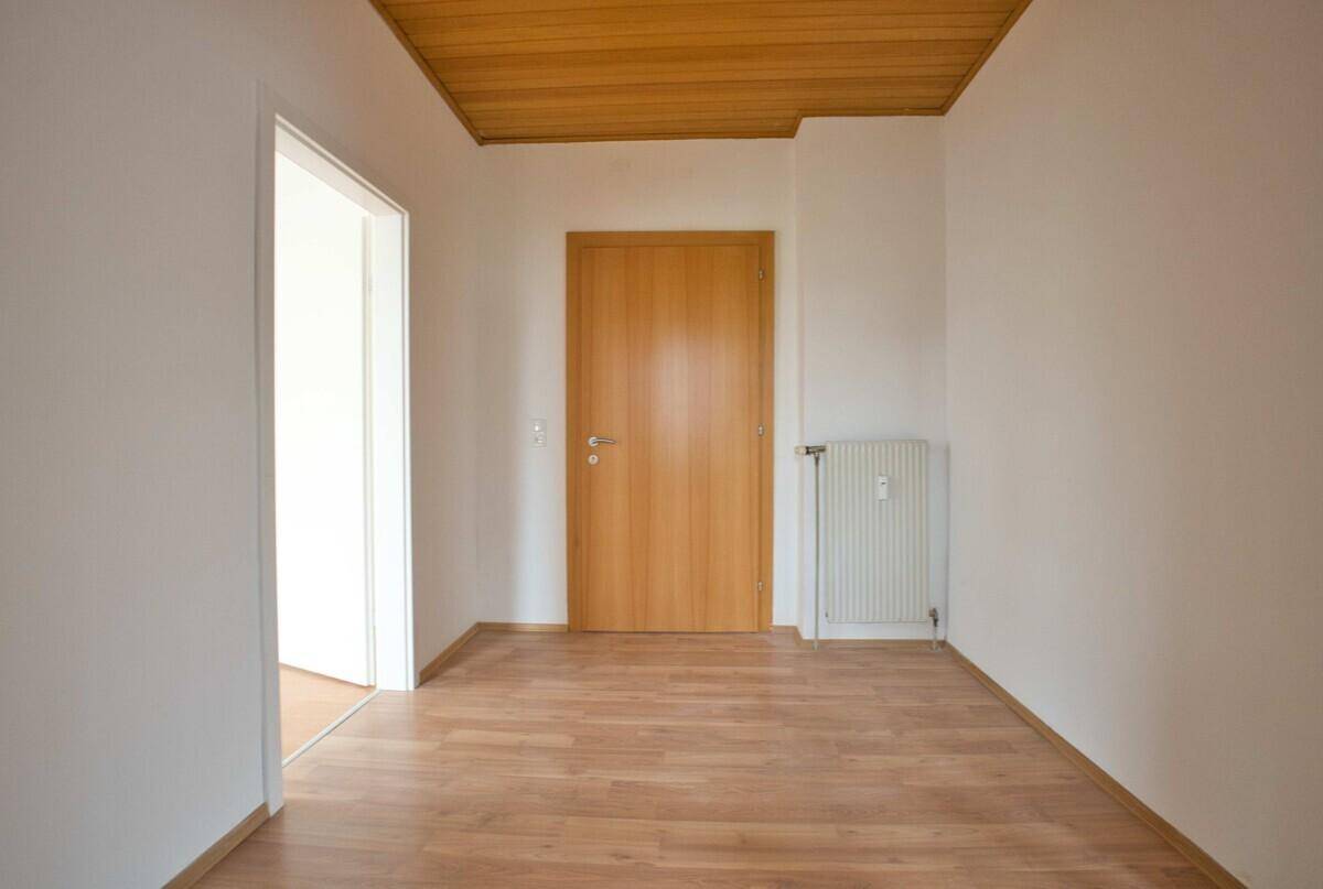 Heller Flur mit Laminatboden und Holztür, der zu den Wohnbereichen führt.