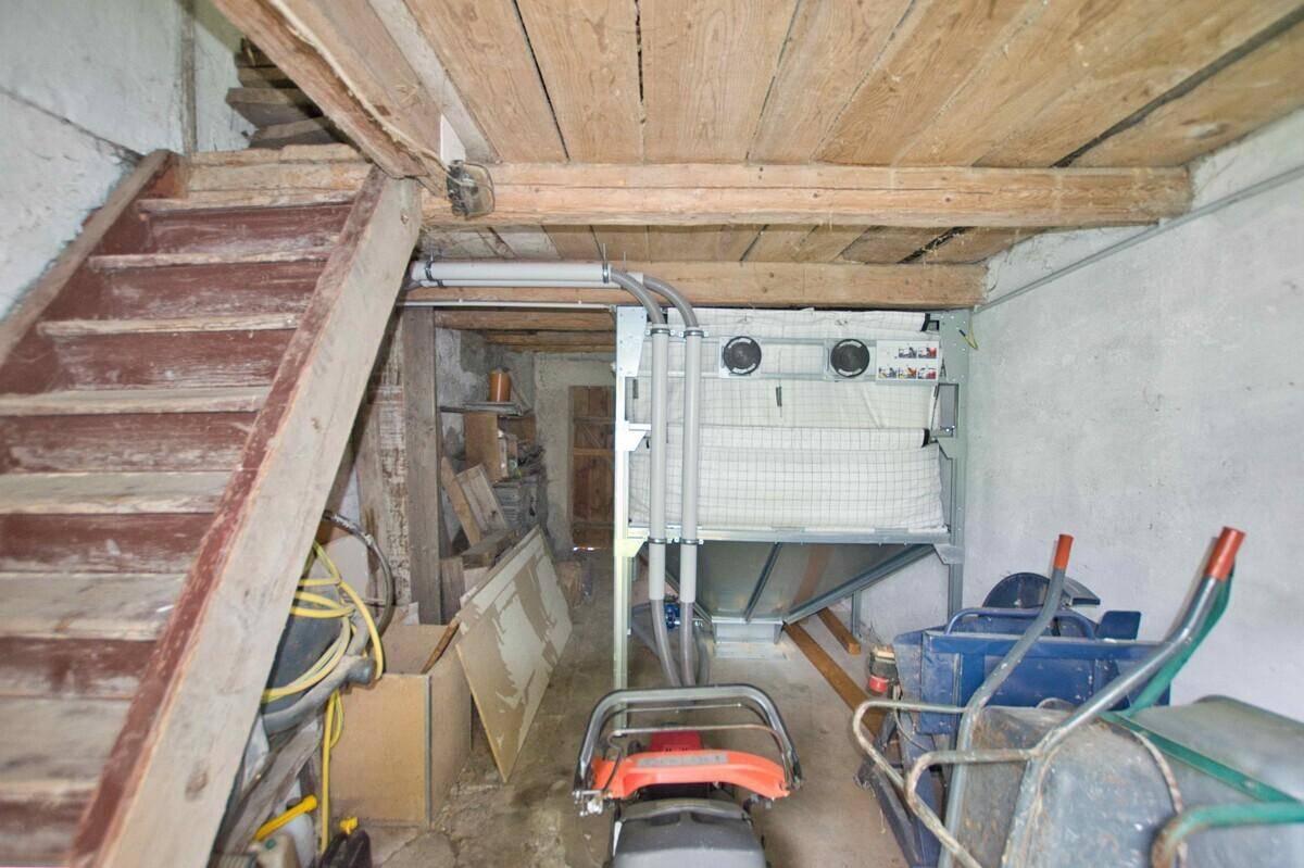 Kellerraum mit Holztreppe, Lagerfläche und verschiedenen Geräten.