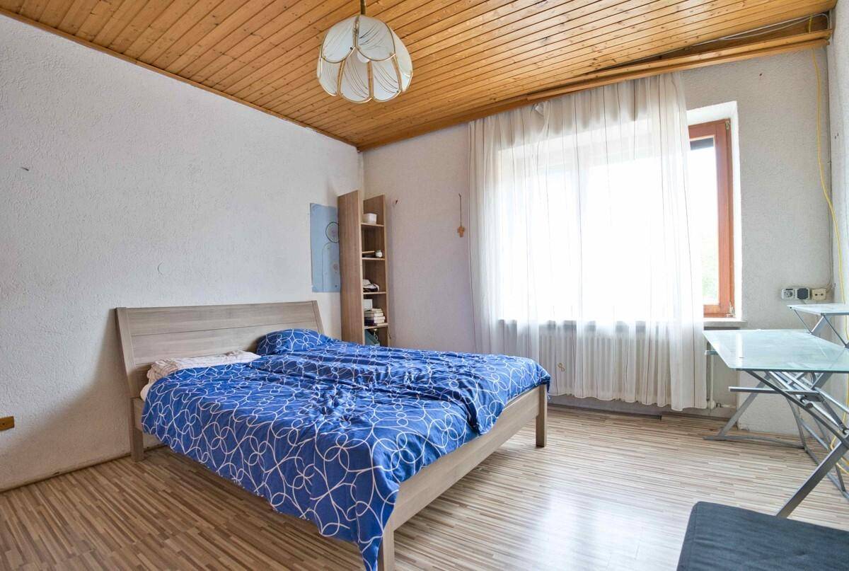 Schlafzimmer mit Holzbett, Holzdeckenverkleidung und hellem Laminatboden, gemütlich und hell.