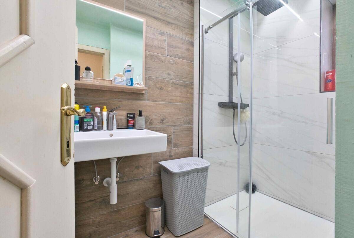 Modernes Badezimmer mit begehbarer Dusche, Holzoptik-Fliesen und Einzelwaschbecken.