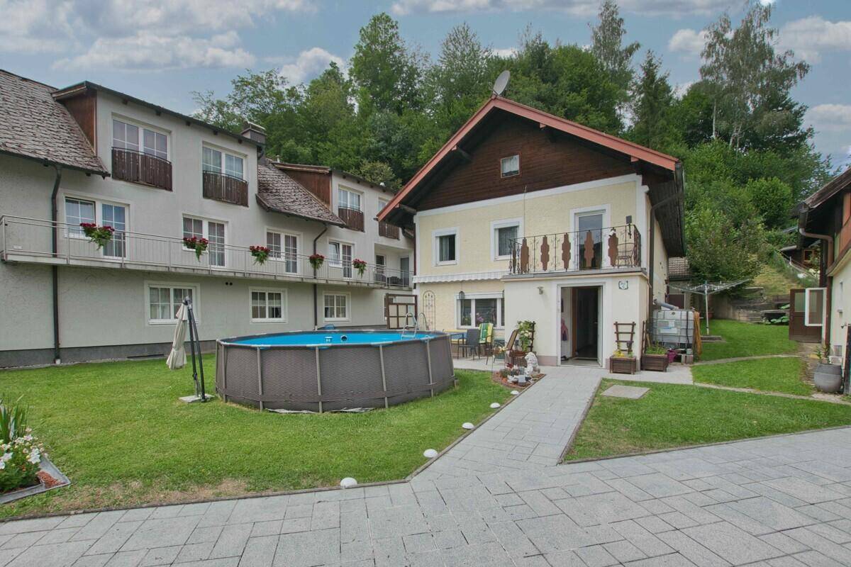 Außenansicht des Hauses mit Garten, oberirdischem Pool und gepflastertem Weg.