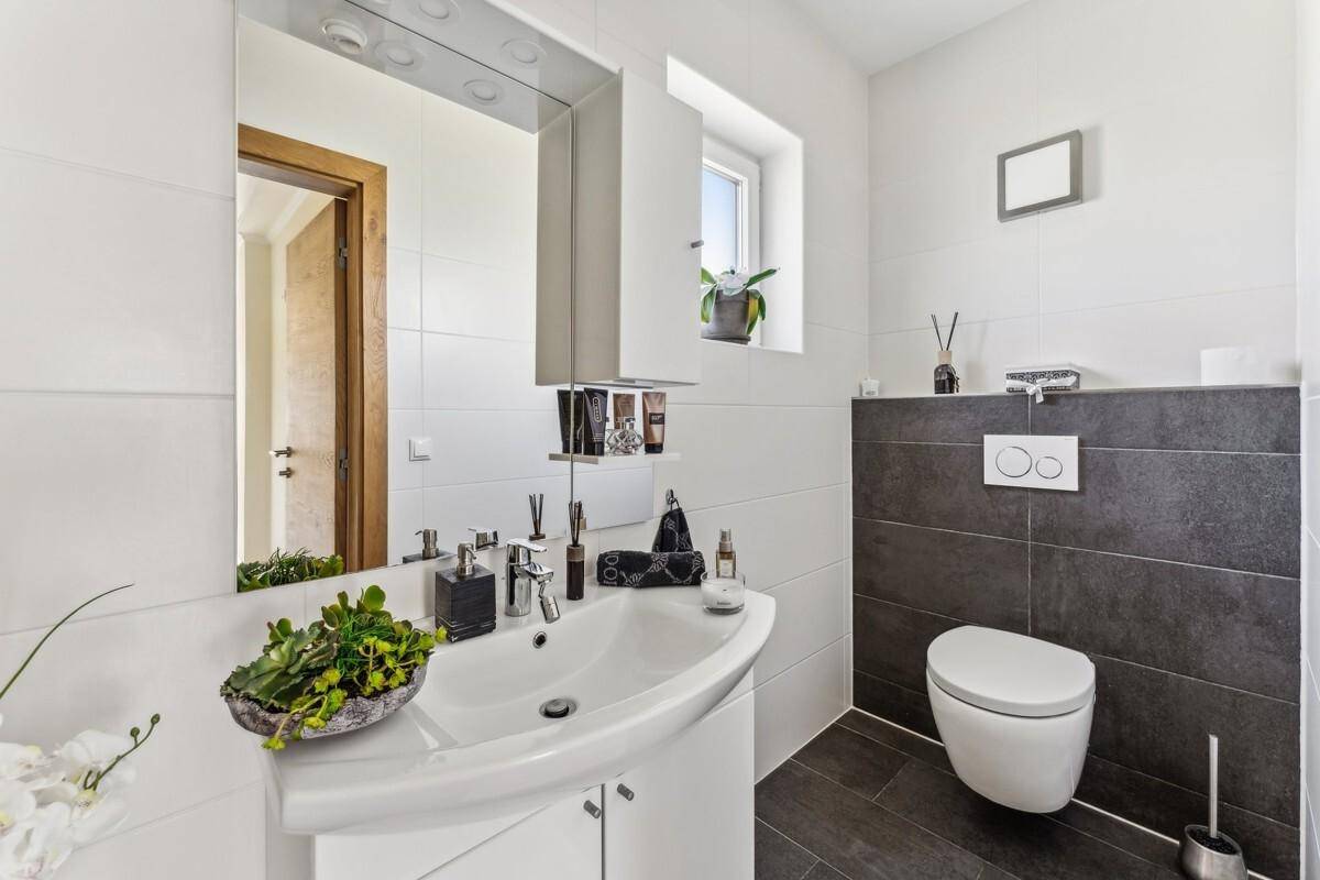 Modernes Badezimmer mit Waschbecken, Spiegel und wandhängendem WC.