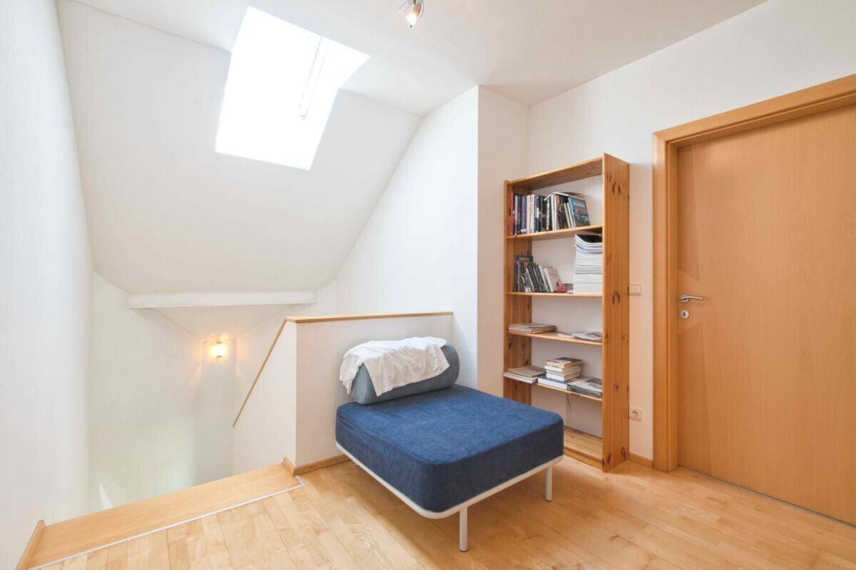 Lichtdurchfluteter Flurbereich mit Dachfenster, Holzboden und Zugang zur Treppe.