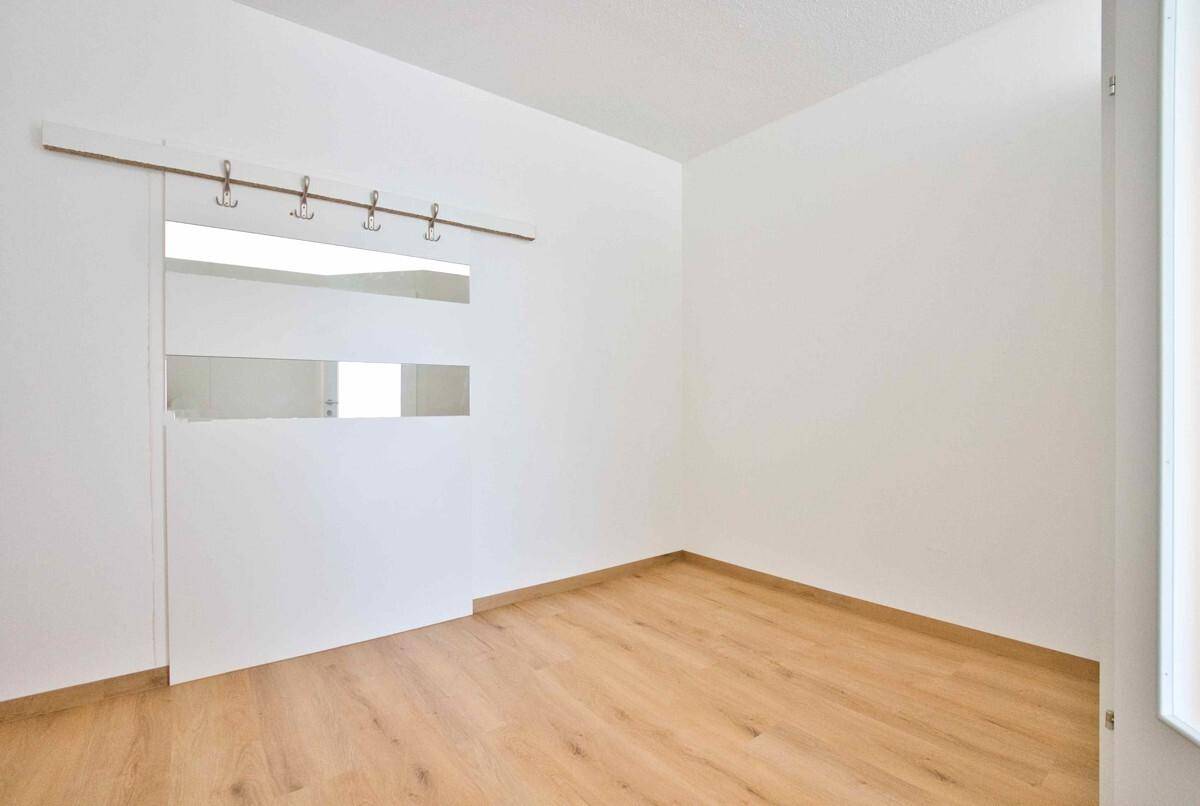 Eingangsbereich oder Flur mit Laminatboden, weißen Wänden und einer Garderobe mit Spiegeln.