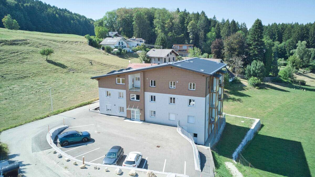 Neubau-Wohngebäude mit moderner Fassade und ausreichend Parkplätzen im Grünen.