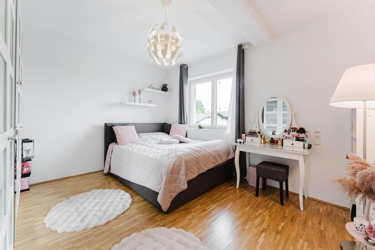 Stilvolles Schlafzimmer mit Schminktisch, Doppelbett und Holzboden, hell und einladend.